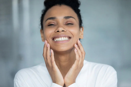 Smiling woman with glowing skin gently touching her face
